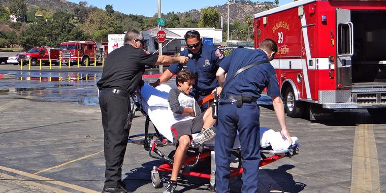 EMS clinicians move a patient on a stretcher near an ambulance