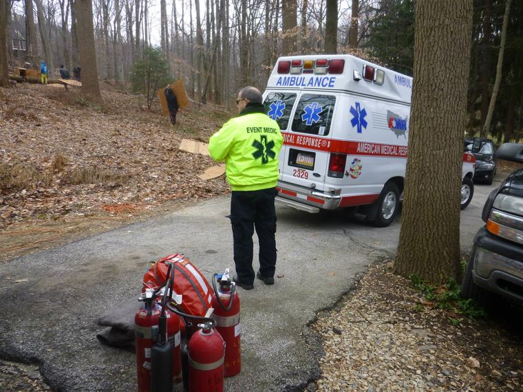 An event medic stages gear beside an ambulance at an outdoor event