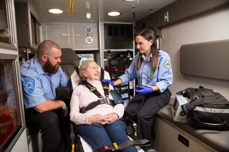 Two EMTs care for a seated patient inside an ambulance