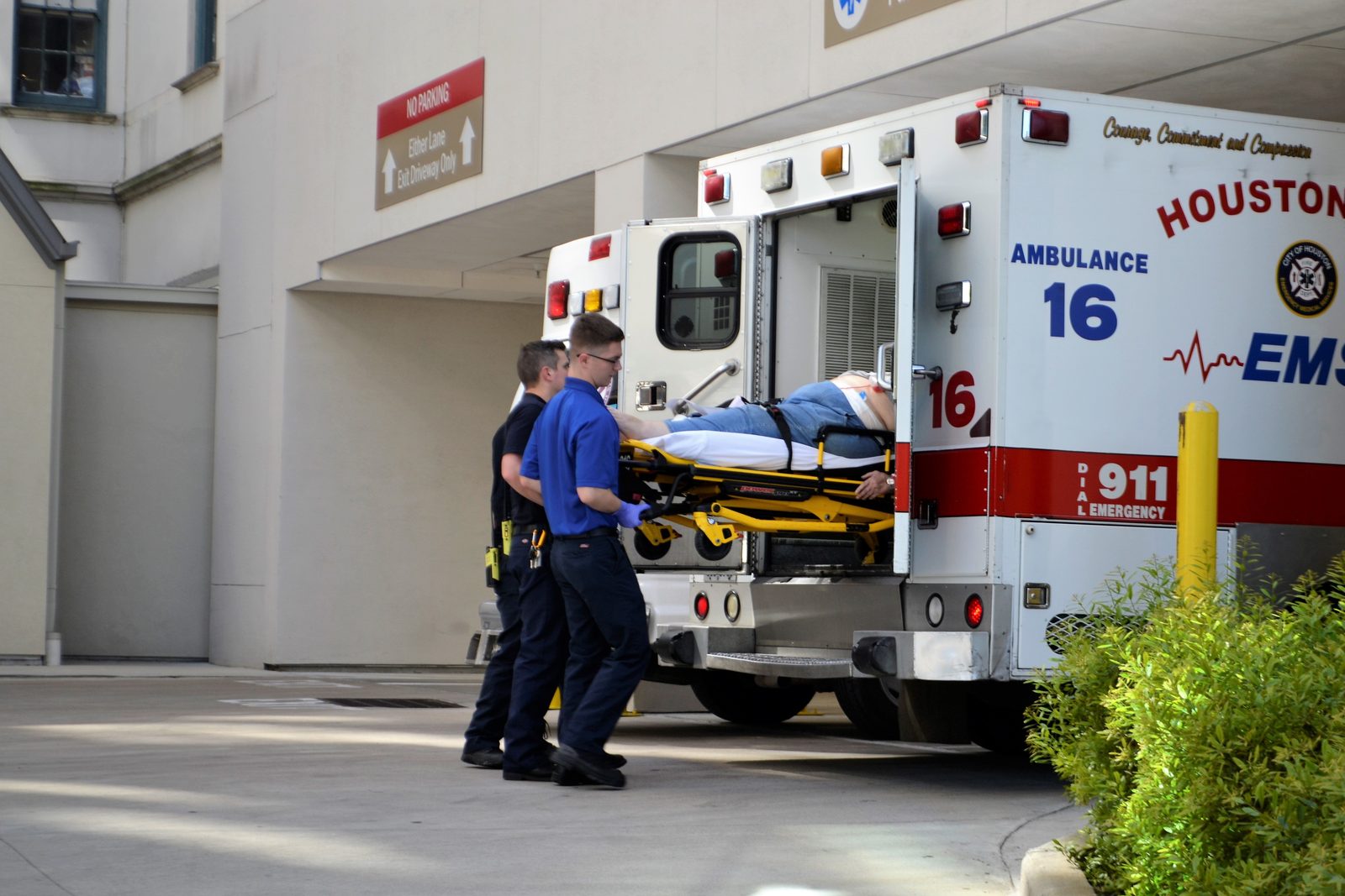 Two EMS clinicians load a patient into the back of an ambulance at a hospital entrance